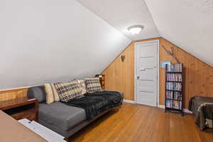 Interior space with wood walls, a textured ceiling, wood-type flooring, and vaulted ceiling