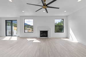 Unfurnished living room with a wealth of natural light, ceiling fan, and light hardwood / wood-style floors