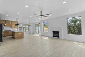 Living room with ceiling fan with notable chandelier, light hardwood / wood-style flooring, and sink