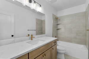 Full bathroom featuring tiled shower / bath combo, vanity, and toilet