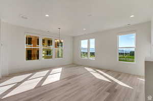 Spare room featuring light hardwood / wood-style flooring and a chandelier