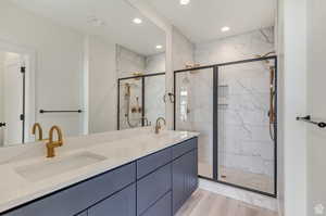 Bathroom with double vanity, walk in shower, and hardwood / wood-style floors