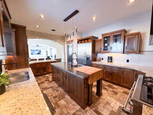 Kitchen featuring high quality fridge, pendant lighting, sink, and a kitchen island with sink