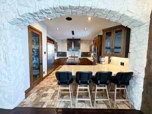 Kitchen with a breakfast bar, stainless steel built in refrigerator, sink, and kitchen peninsula