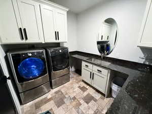 Laundry room with washing machine and clothes dryer, sink, cabinets, and light tile patterned floors