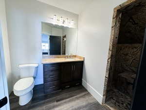 Bathroom with hardwood / wood-style flooring, a shower, toilet, and vanity