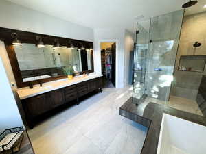 Bathroom with double sink vanity, an enclosed shower, and tile patterned flooring