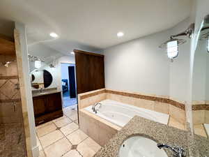 Bathroom featuring tile patterned flooring, shower with separate bathtub, and vanity