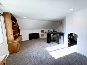 Carpeted home office with vaulted ceiling and built in features