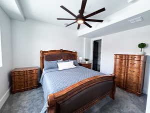 Carpeted bedroom featuring a spacious closet and ceiling fan