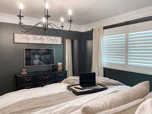 Bedroom with an inviting chandelier, a textured ceiling, and crown molding