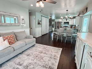 Living room featuring dark hardwood / wood-style floors, ceiling fan with notable chandelier, and a textured ceiling