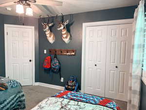 Carpeted bedroom featuring a textured ceiling, a closet, and ceiling fan