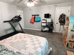 Carpeted bedroom featuring a textured ceiling and ceiling fan