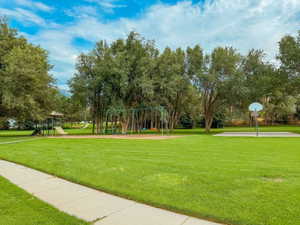 View of home's community featuring a lawn, basketball court, and a playground