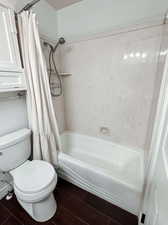 Bathroom with hardwood / wood-style floors, toilet, and shower / bath combo