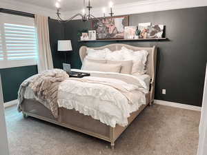 Bedroom featuring an inviting chandelier, carpet floors, and crown molding