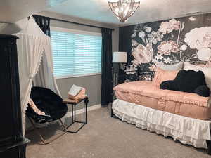 Carpeted bedroom featuring an inviting chandelier and a textured ceiling