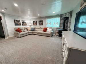 Carpeted living room featuring a wood stove and a textured ceiling