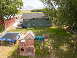 Rear view of house with a playground, a lawn, and a mountain view