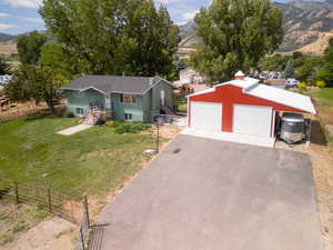 View of front of house featuring an outbuilding, a front lawn, a rural view, a garage, and a mountain view