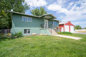 View of front of home with a garage, an outdoor structure, and a front yard