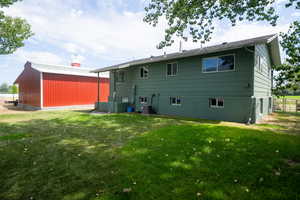 Back of house featuring central AC, a lawn, and an outdoor structure