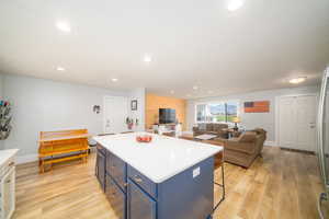 Kitchen featuring a kitchen breakfast bar, a center island, blue cabinetry, and light laminate flooring