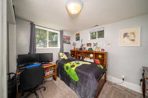 Bedroom with light colored carpet and a textured ceiling