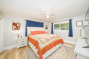 Bedroom with ceiling fan and light laminate floors