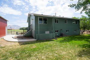 Rear view of property with a mountain view, central air condition unit, a patio, and a lawn