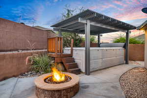 Patio terrace at dusk featuring an outdoor fire pit and a pergola