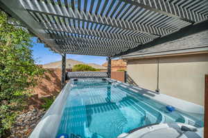 View of swimming pool featuring a pergola and a hot tub