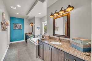 Bathroom with tile patterned flooring, tiled bath, and vanity