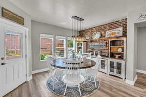 Dining space with brick wall and light wood-type flooring