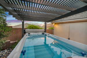 Pool at dusk featuring a pergola