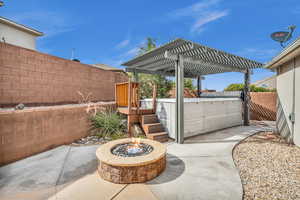 View of patio featuring a pergola, a wooden deck, a hot tub, and a fire pit