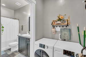 Interior space with washer / dryer, vanity, hardwood / wood-style flooring, and toilet