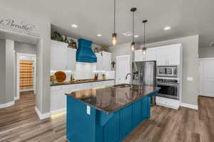 Kitchen featuring decorative backsplash, hardwood / wood-style flooring, stainless steel appliances, and custom range hood