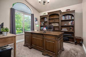 Carpeted home office featuring an inviting chandelier and lofted ceiling