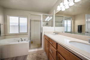 Bathroom featuring double vanity, a healthy amount of sunlight, wood-type flooring, and plus walk in shower