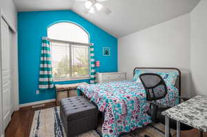 Bedroom with a closet, ceiling fan, vaulted ceiling, and dark wood-type flooring