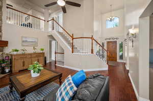 Living room with a towering ceiling, dark hardwood / wood-style flooring, and a wealth of natural light