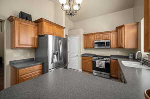 Kitchen with a chandelier, stainless steel appliances, sink, and high vaulted ceiling