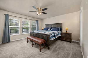 Carpeted bedroom featuring a textured ceiling and ceiling fan