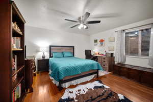 Bedroom with a textured ceiling, ceiling fan, and hardwood / wood-style floors