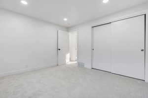 Unfurnished bedroom featuring a closet and light colored carpet