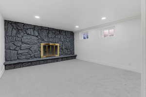 Unfurnished living room featuring a stone fireplace and carpet