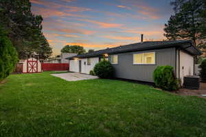 Back house at dusk featuring a patio, central AC, a shed, and a yard