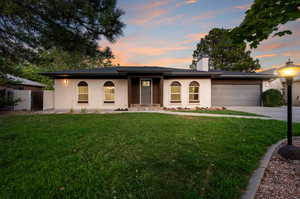 View of front facade featuring a garage and a lawn